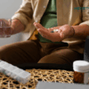 a person holding a pill and a glass of water
