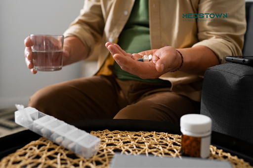 a person holding a pill and a glass of water