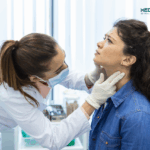 Endocrinologist examining throat of young woman in clinic women with thyroyed