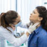 Endocrinologist examining throat of young woman in clinic women with thyroyed