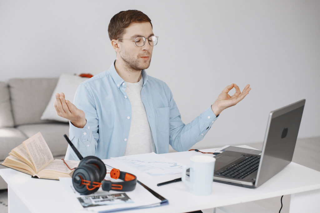 Man sitting in living room at home. Guy enjoying studying using laptop and headset. Meditation.