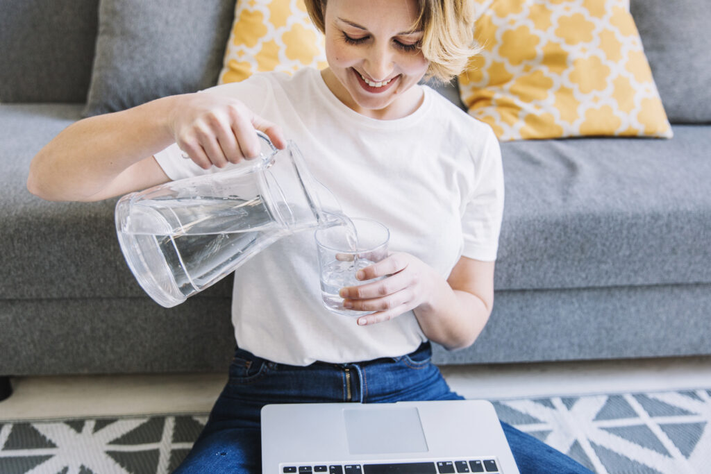 smiling woman with laptop pouring water