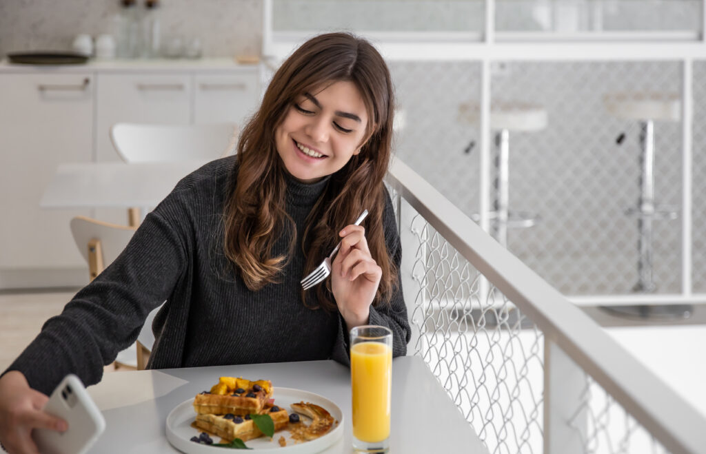 Young woman takes a selfie at breakfast, Belgian waffles and juice for breakfast.