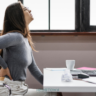 Woman experiencing back pain at desk.