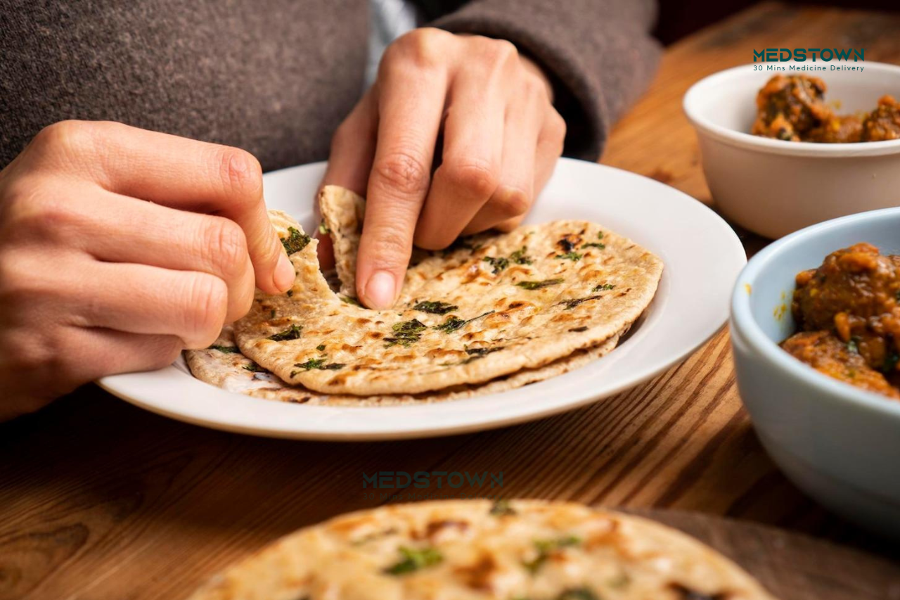 Hands tearing flatbread on plate